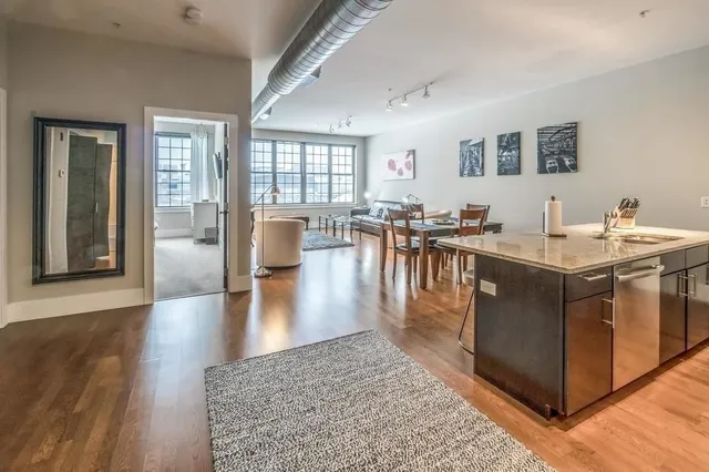 a living room with stainless steel appliances granite countertop a couch a table and chairs