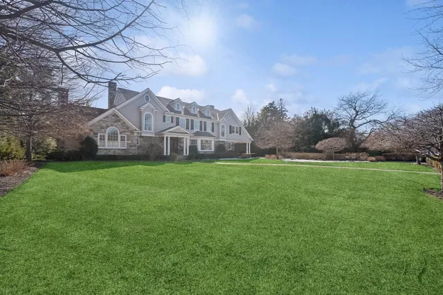 a view of a house with a big yard and large trees