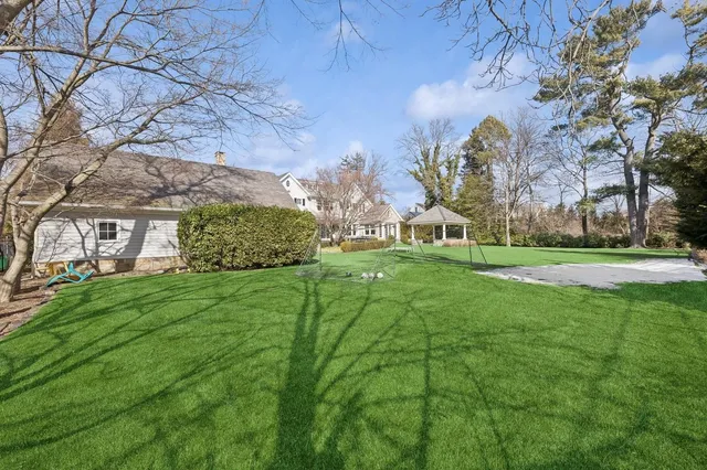 a view of a big house with a big yard and large trees