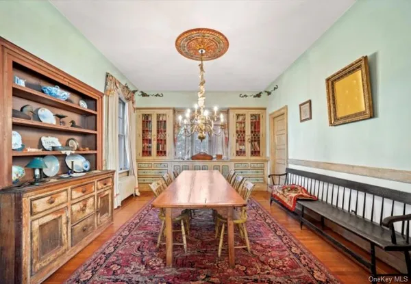 a dining room with wooden floor and large windows