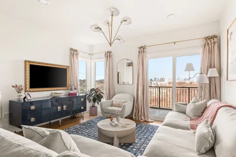 a living room with furniture a flat screen tv and a large window