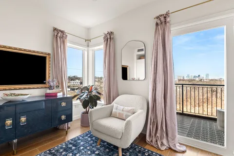 a living room with furniture a flat screen tv and floor to ceiling window