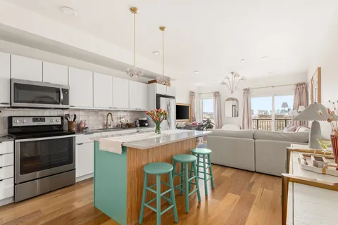 a open kitchen with granite countertop a stove top oven a sink dishwasher and white cabinets with wooden floor