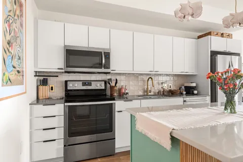 a kitchen with stainless steel appliances granite countertop a stove a sink and a microwave
