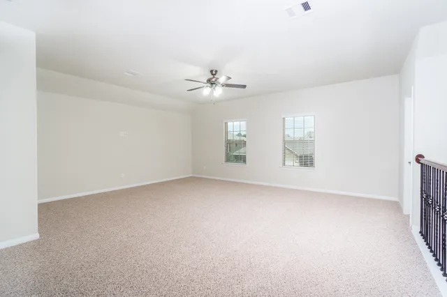 an empty room with windows and chandelier fan