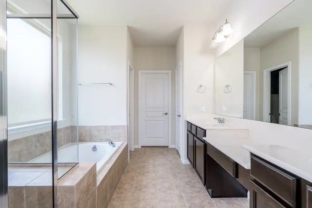 a large bathroom with a tub sink shower and mirror