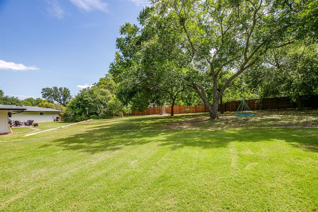 6700 Fortune Road Fort Worth, TX 76116 - Photo 36 of 40 Spacious backyard featuring a large tree providing ample shade, mature perimeter trees, a wood privacy fence, and a generous grass area