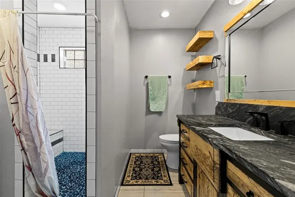 a bathroom with a granite countertop sink and a toilet