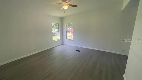 an empty room with windows and fan