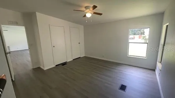 a view of empty room with wooden floor and fan