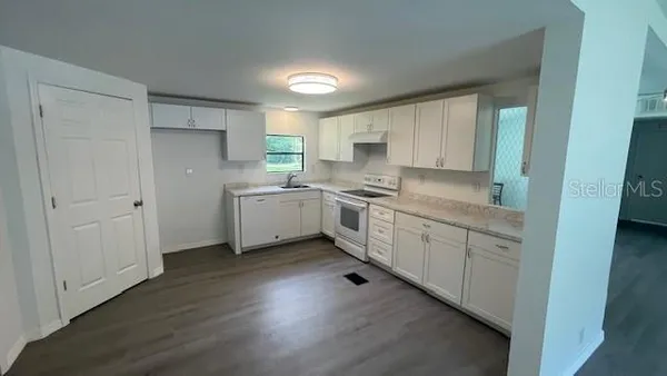 a kitchen with white cabinets appliances and a window