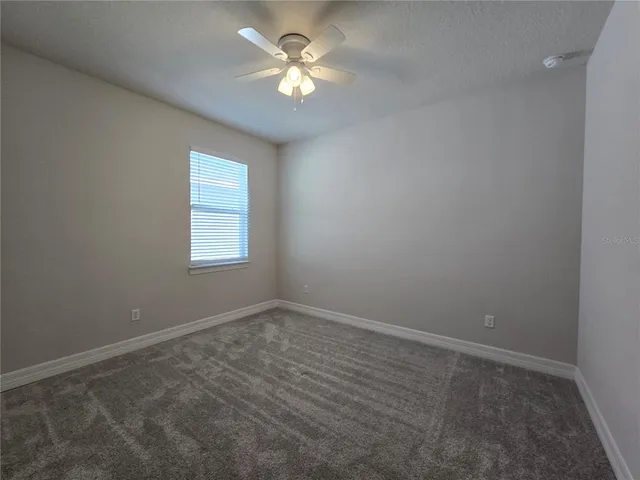 an empty room with a window and a fan