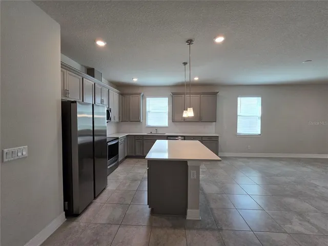 a kitchen with kitchen island granite countertop a refrigerator and a sink