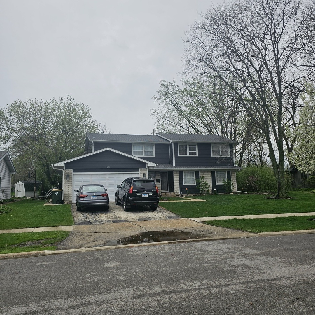 128 Essex Road Elk Grove Village, IL 60007 - Photo 2 of 18 a car parked in front of a brick house next to a yard