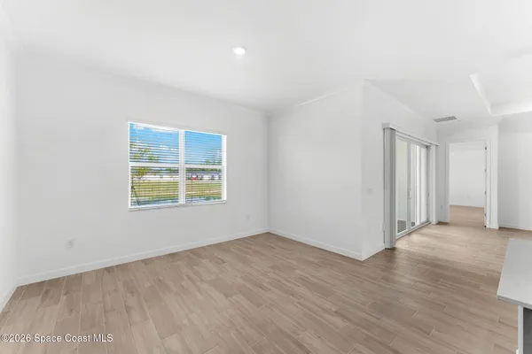 an empty room with wooden floor and natural light