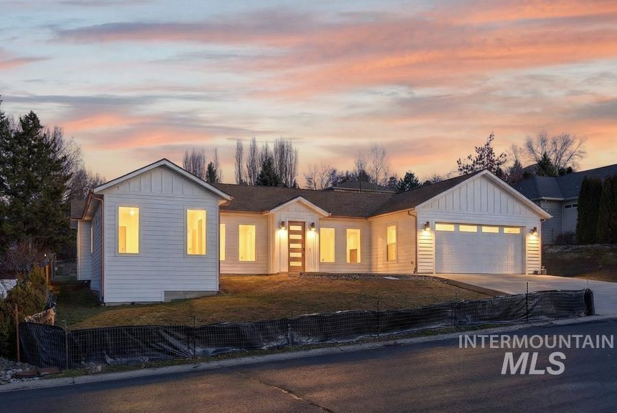 View of front of house with board and batten siding, a garage, concrete driveway, and a front yard