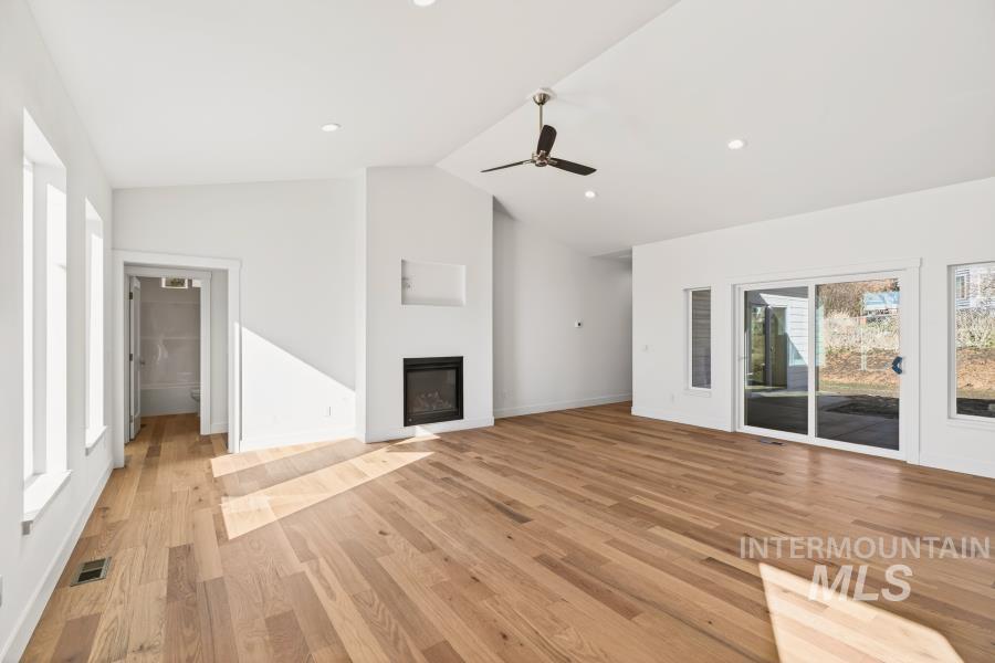780 Victoria Drive Moscow, ID 83843 - Photo 12 of 44 Unfurnished living room with ceiling fan, light wood finished floors, a glass covered fireplace, a high ceiling, and recessed lighting