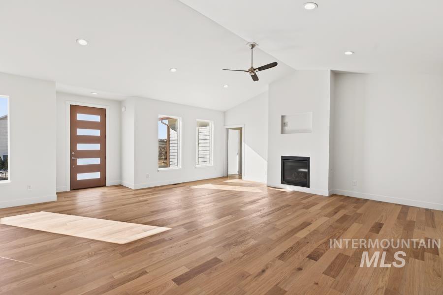 780 Victoria Drive Moscow, ID 83843 - Photo 13 of 44 Unfurnished living room featuring a ceiling fan, light wood-type flooring, a glass covered fireplace, lofted ceiling, and recessed lighting