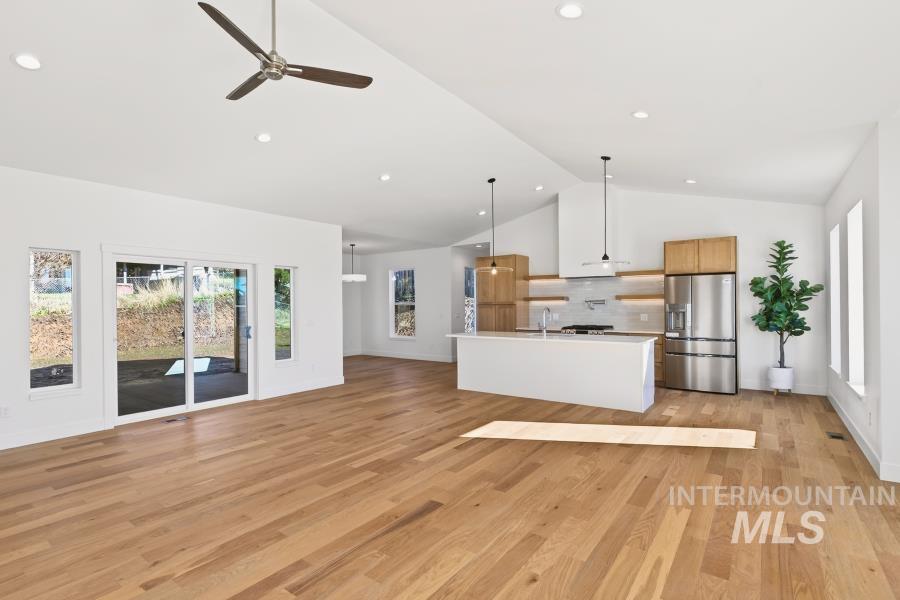 780 Victoria Drive Moscow, ID 83843 - Photo 44 of 44 Kitchen featuring stainless steel refrigerator with ice dispenser, light countertops, open floor plan, a ceiling fan, and a kitchen island with sink