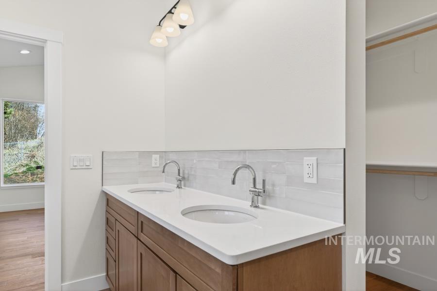 780 Victoria Drive Moscow, ID 83843 - Photo 27 of 44 Bathroom with double vanity, backsplash, and wood finished floors