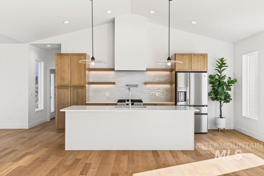 780 Victoria Drive Moscow, ID 83843 - Photo 6 of 44 Kitchen featuring stainless steel refrigerator with ice dispenser, decorative light fixtures, lofted ceiling, a kitchen island with sink, and light wood finished floors