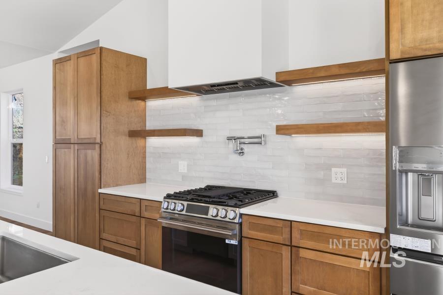 780 Victoria Drive Moscow, ID 83843 - Photo 8 of 44 Kitchen with wood finish cabinetry, stainless steel appliances, tasteful backsplash, open shelves with inset LED's, pot filler faucet, and light quartz counters