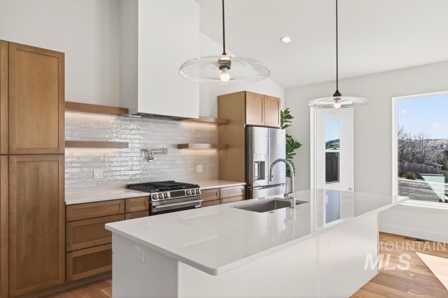 780 Victoria Drive Moscow, ID 83843 - Photo 9 of 44 Kitchen with wood finish cabinetry, an island with sink, light wood-style flooring, pendant lighting, and vaulted ceiling