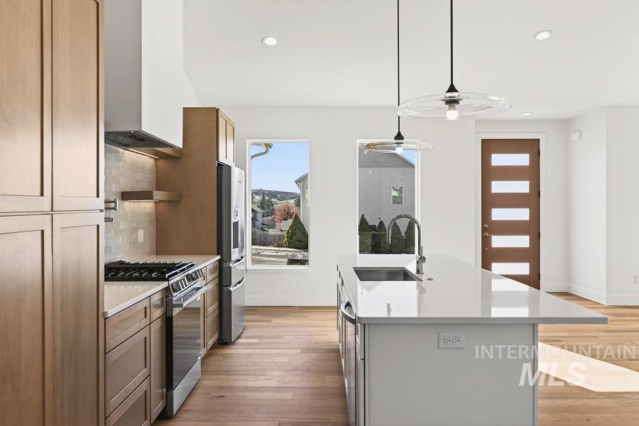 780 Victoria Drive Moscow, ID 83843 - Photo 10 of 44 Kitchen featuring an island with sink, stainless steel appliances, light wood-type flooring, pendant lighting, and light stone countertops