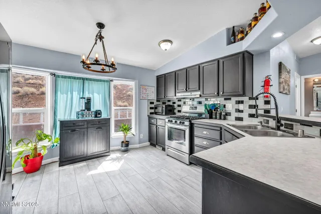 a kitchen with stainless steel appliances granite countertop a sink dishwasher a microwave oven and a dining table with wooden floor