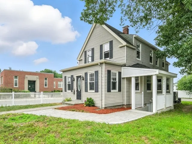 a front view of a house with a yard and potted plants