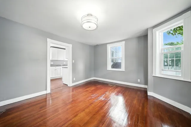 a view of an empty room with window and wooden floor