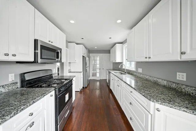a large kitchen with stainless steel appliances granite countertop a stove a sink and a microwave