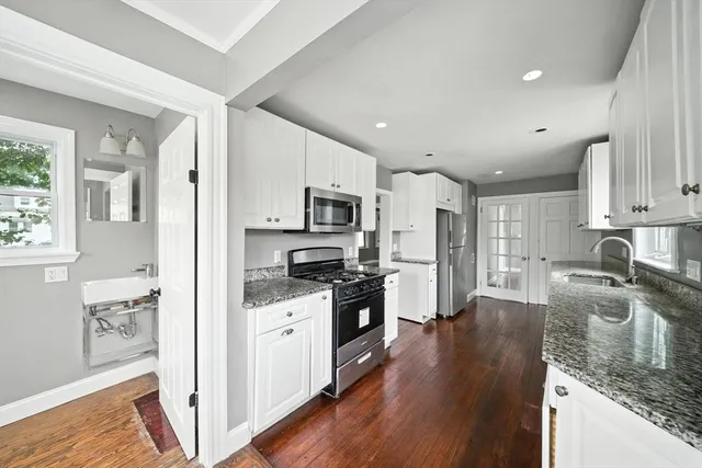 a kitchen with stainless steel appliances granite countertop a refrigerator a stove top oven a sink dishwasher and white cabinets with wooden floor