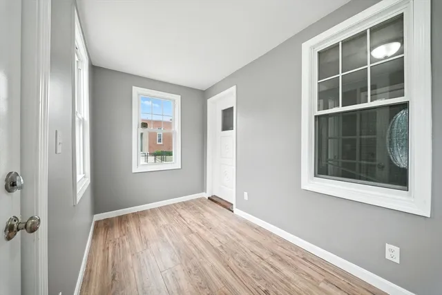 a view of an empty room with a window and wooden floor