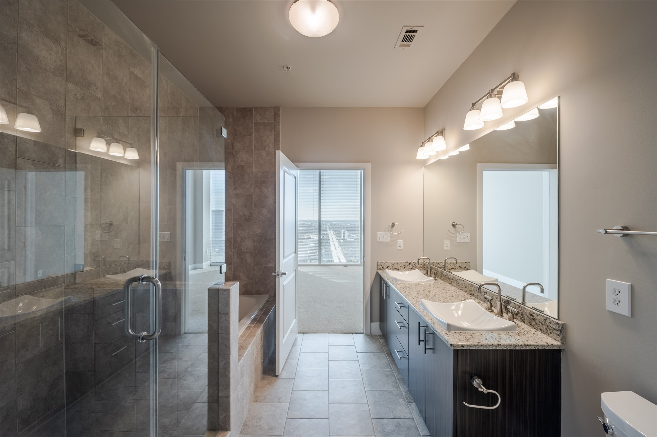 5927 Almeda Road, Unit 22909 Houston, TX 77004 - Photo 5 of 8 a bathroom with a granite countertop sink a toilet a mirror and vanity