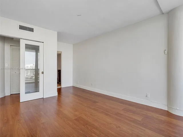 a view of a living room with a floor to ceiling window and wooden floor