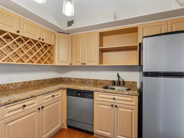 a kitchen with granite countertop a refrigerator a sink dishwasher a stove and a refrigerator with wooden floor