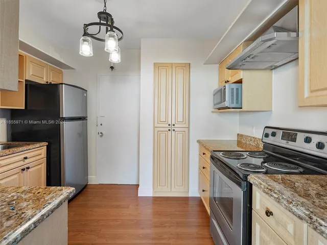 a view of an empty room with wooden floor and cabinets