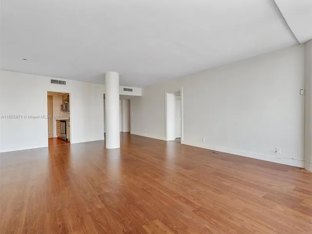 a view of empty room with wooden floor and floor to ceiling window