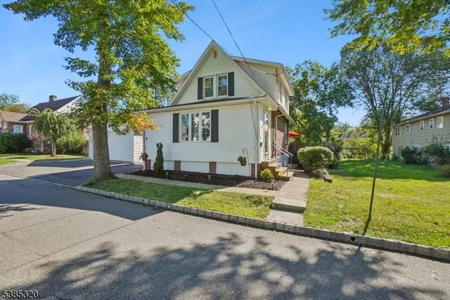 a front view of a house with garden and trees