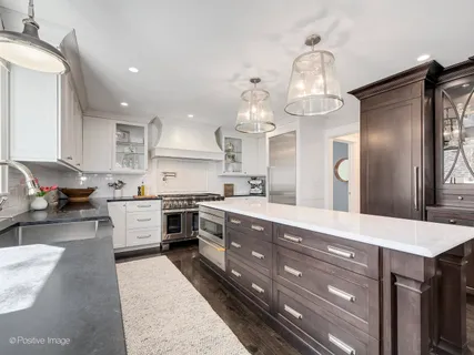 a large kitchen with stainless steel appliances granite countertop a lot of counter space and wooden floor
