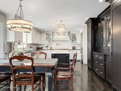 a kitchen with stainless steel appliances granite countertop a stove a refrigerator a oven a dining table and chairs with wooden floor