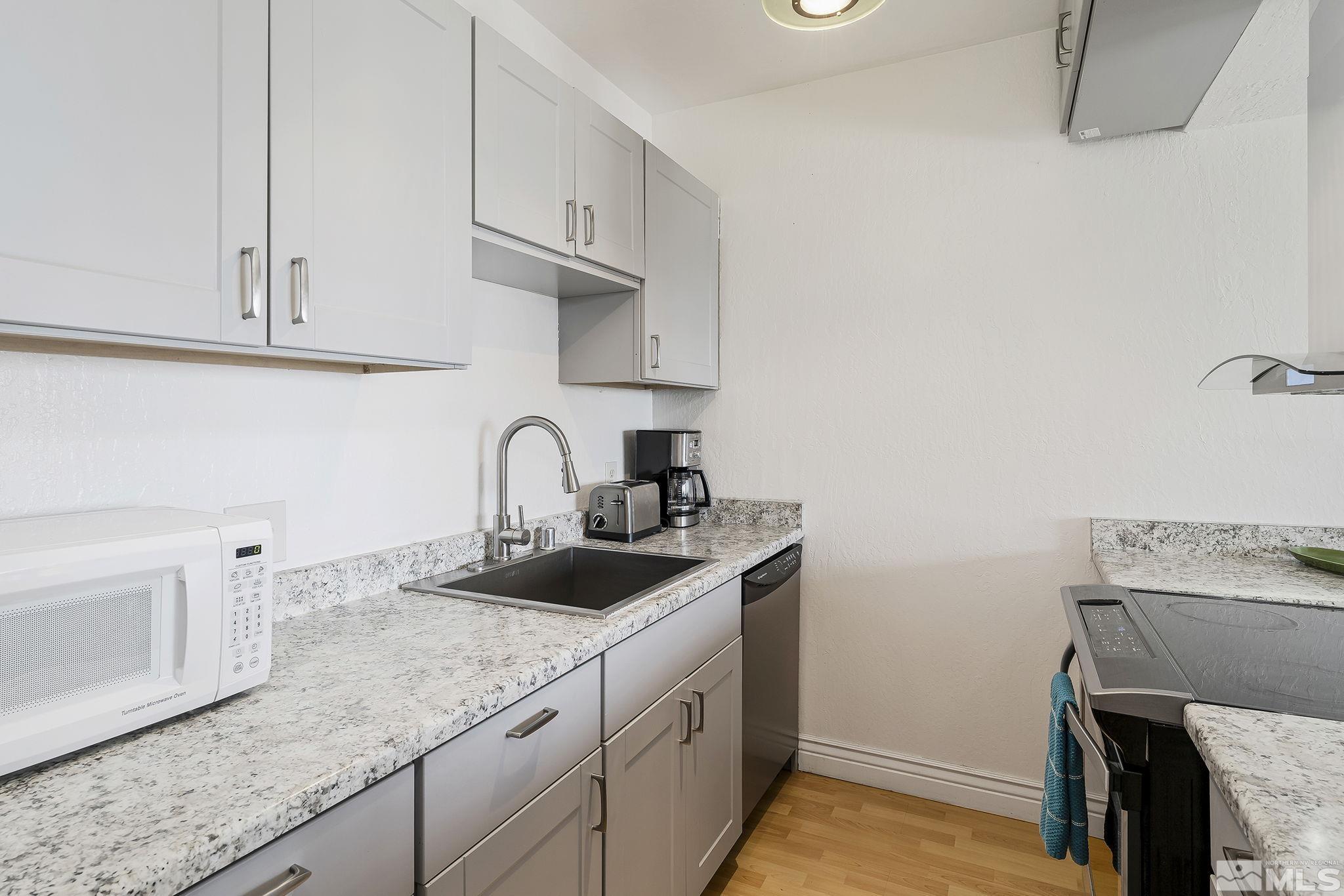 313 Tramway Drive, Unit 13 Stateline, NV 89449 - Photo 15 of 24 a kitchen with granite countertop white cabinets and a sink
