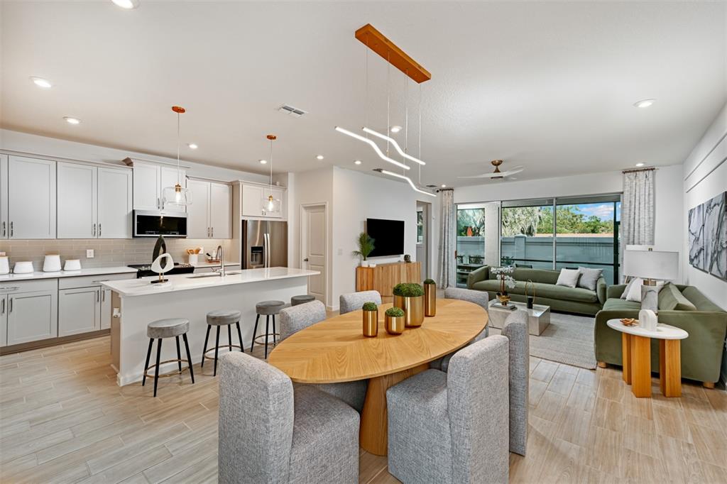 3358 Timber Xing Avenue Brandon, FL 33511 - Photo 7 of 22 a kitchen with stainless steel appliances kitchen island granite countertop a stove a sink a dining table and chairs with wooden floor