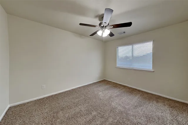 an empty room with a window and a fan