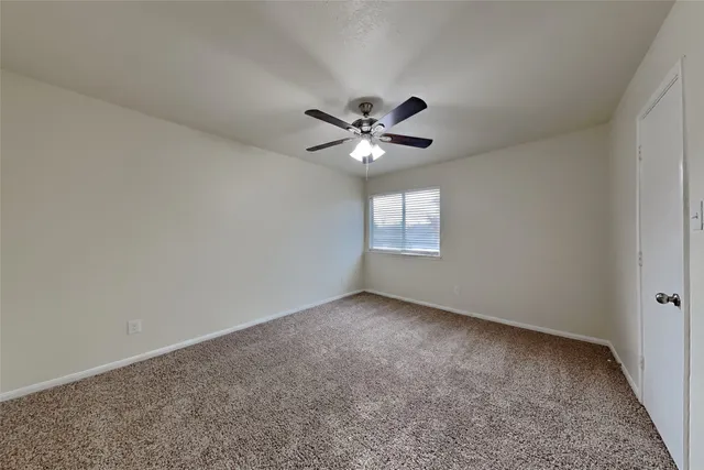 an empty room with a ceiling fan and a window