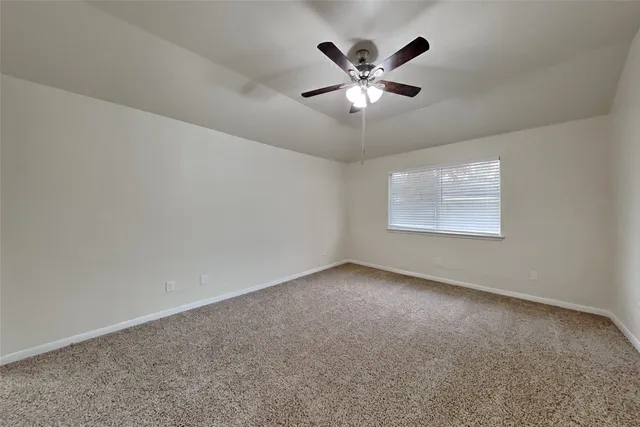 a view of an empty room with a chandelier fan
