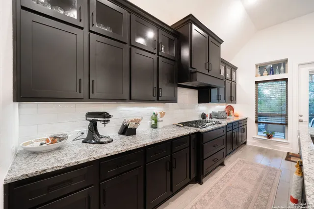 a kitchen with granite countertop a refrigerator and a stove top oven