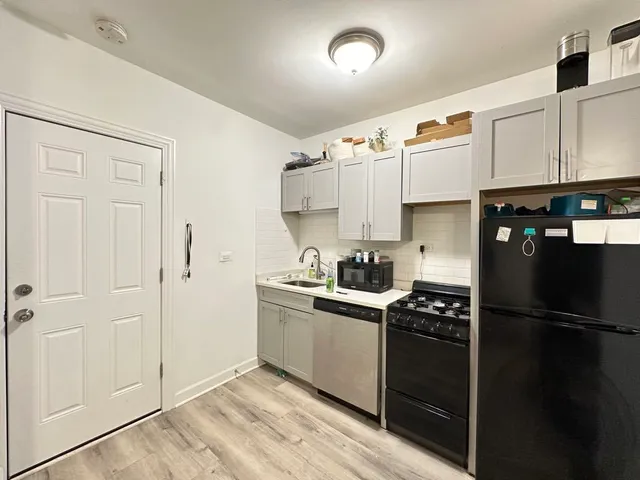 a kitchen with a refrigerator and white cabinets