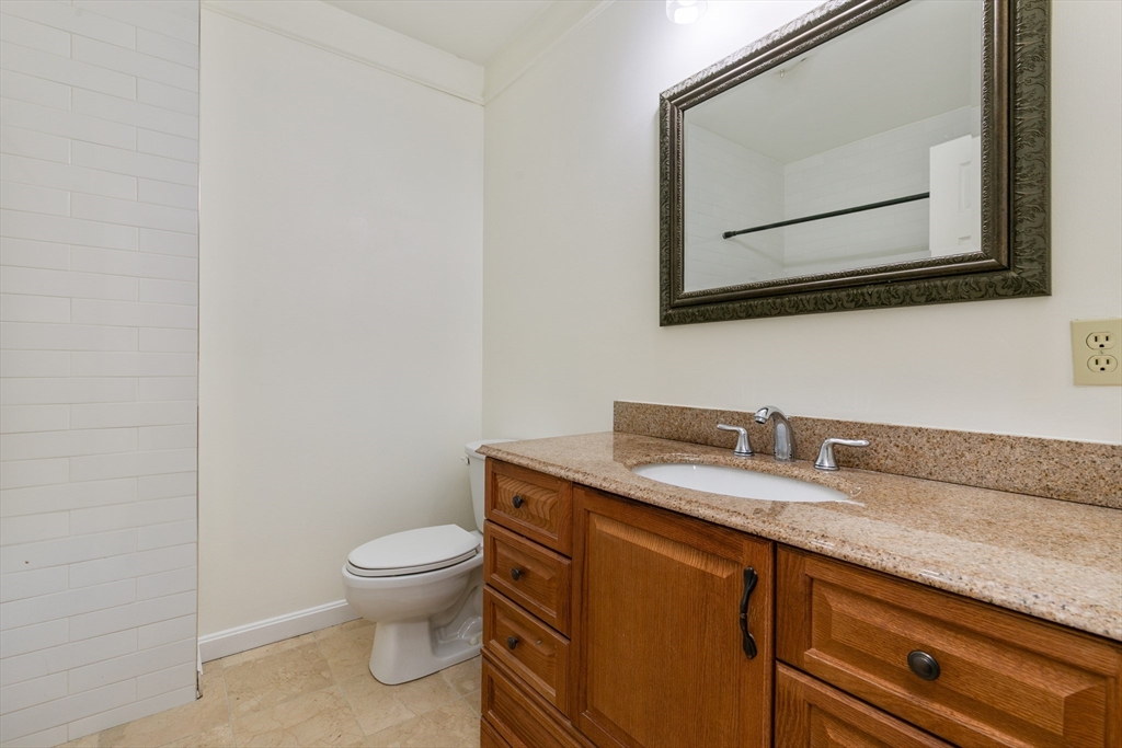 128 Warren Street, Unit 12 Lowell, MA 01852 - Photo 14 of 24 a bathroom with a granite countertop toilet sink and mirror
